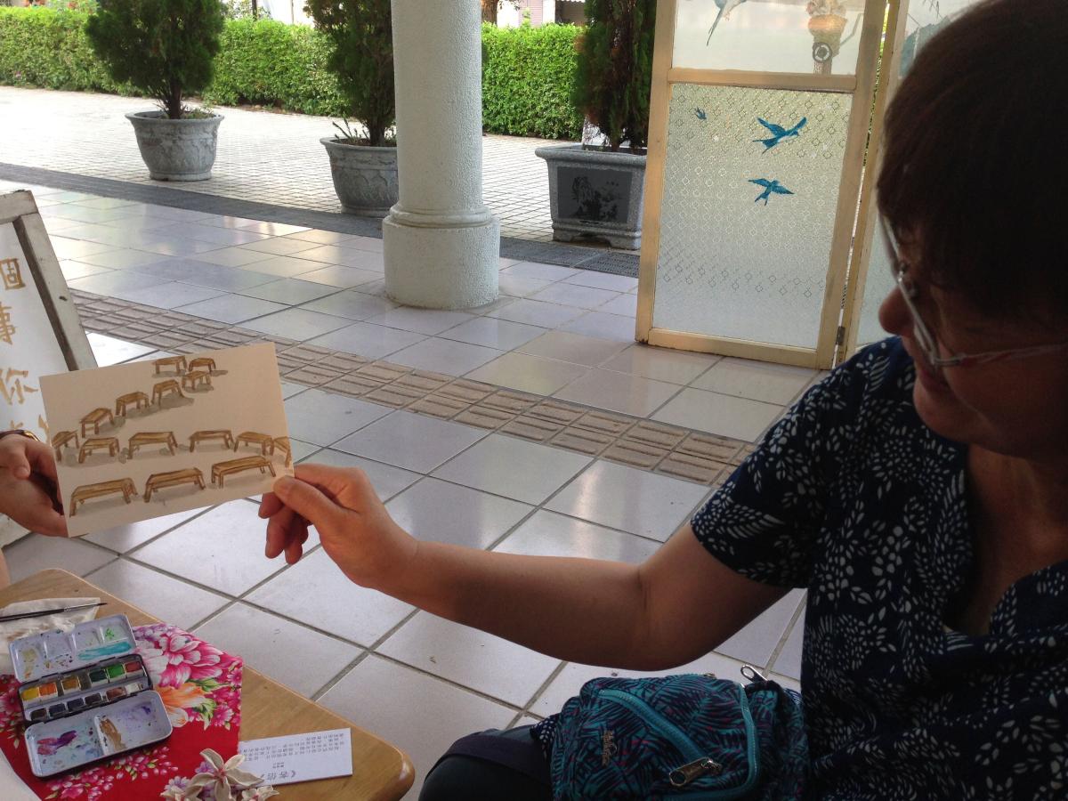 A local woman receives a postcard hand drawn by a visiting Incarnate artist at an art exhibit put on by OM in Taiwan.